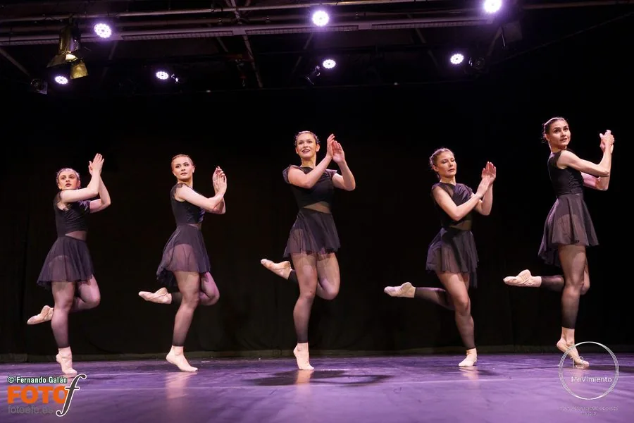 Alumnas de In Stage en el escenario, todas a la vez con una pierna doblada y las manos juntas, bajo los focos de un certamen de danza
