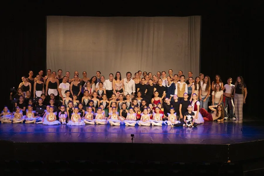 Toda la escuela en el escenario al final del festival, las peques sentadas delante y las mayores detrás
