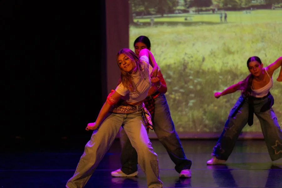 Tres bailarinas de danza urbana con pantalón ancho y top blanco, en pleno paso sobre el escenario del festival de In Stage
